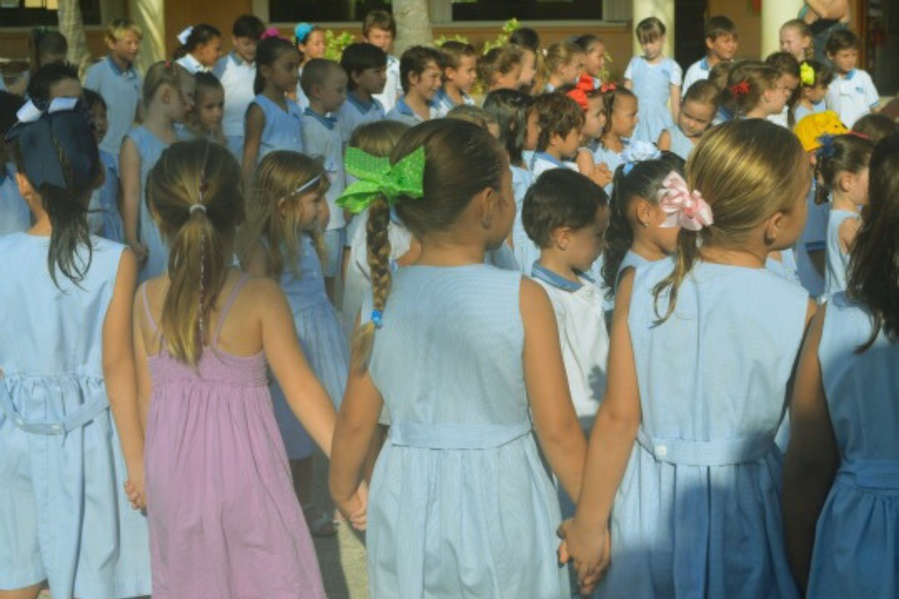 children in uniforms lining up for school and holding hands